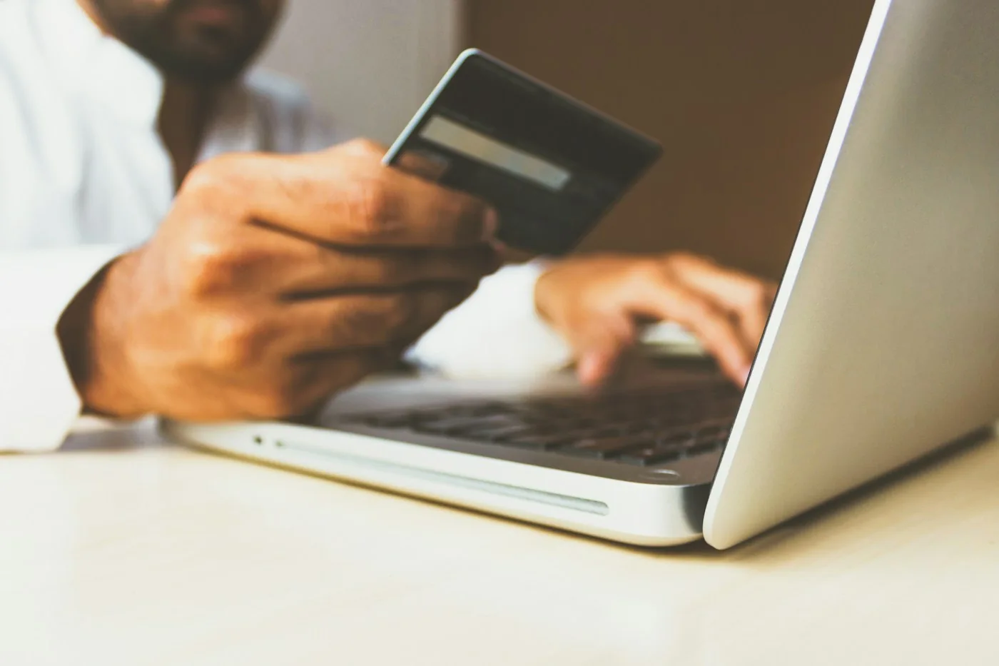 Persona ingresando los datos de una tarjeta en una laptop para pagar online