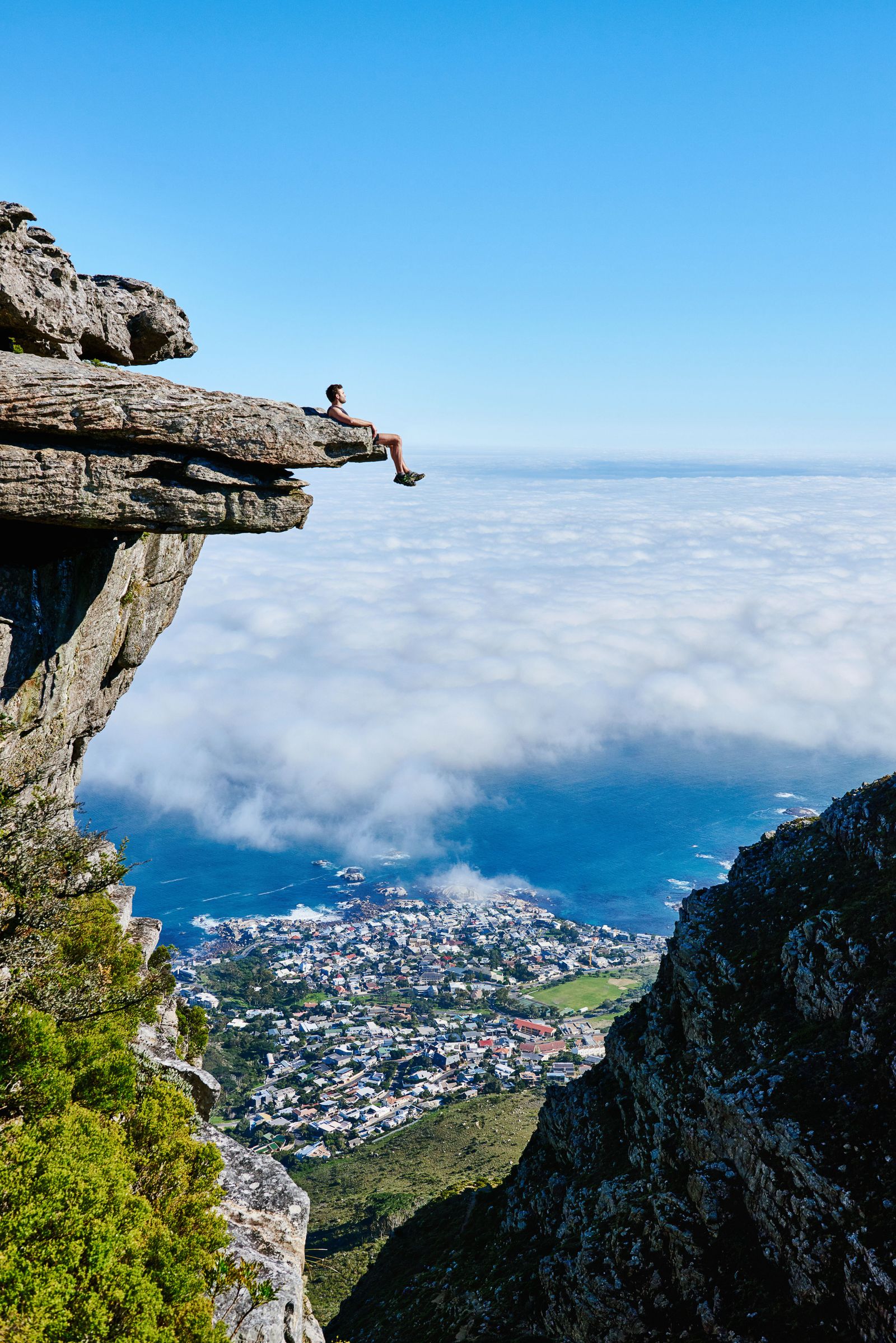 Persona junto a un mirador rocoso sobre las nubes