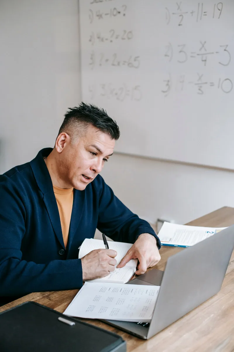 Docente preparando una clase con su computador y apuntes